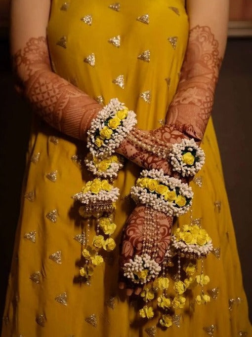 Bride women wearing yellow dress for haldi and wear a Flower Jewellery Kalire on that for her ceremony.  