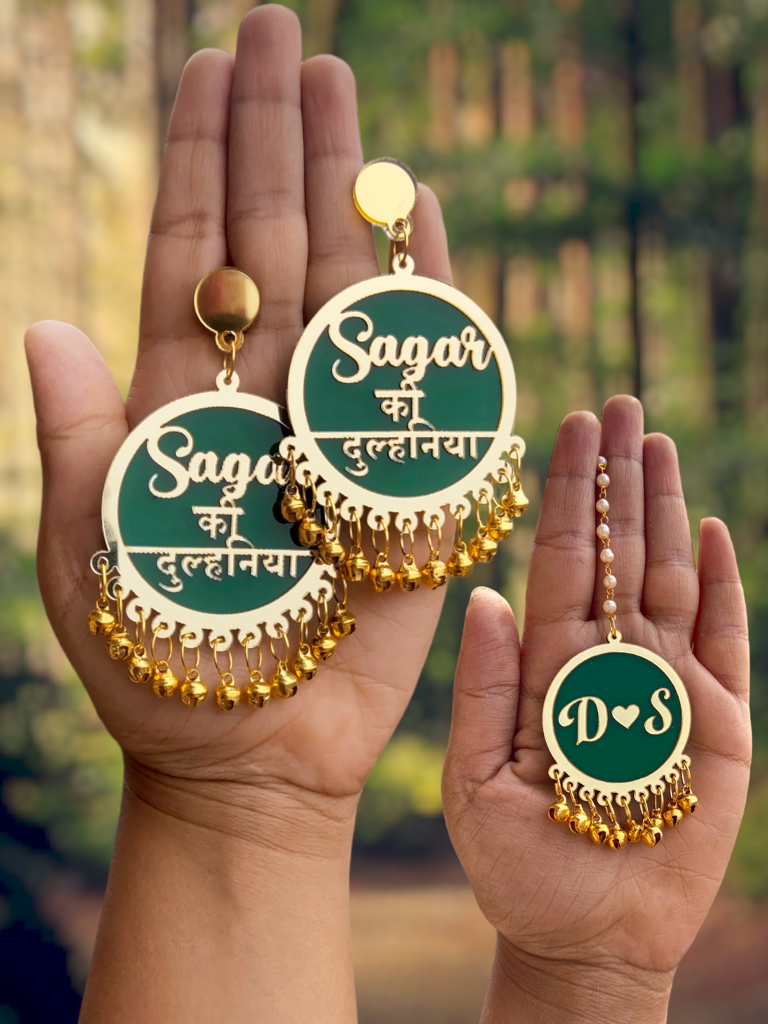 Golden Ghungroo-embellished Dulhaniya earrings and a small green maang tikka. Customized text in golden adds a personalized touch. The intricate design includes a tassel of golden Ghungroo (bells), adding a unique and elegant element to the bridal accessories